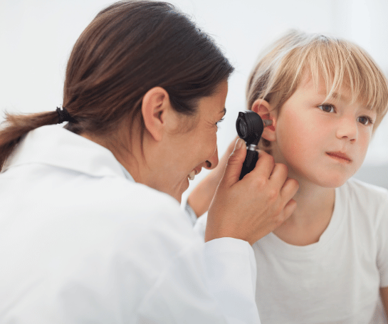 Licensed audiologist performing an otoscopic ear examination on a patient before audiometric testing
