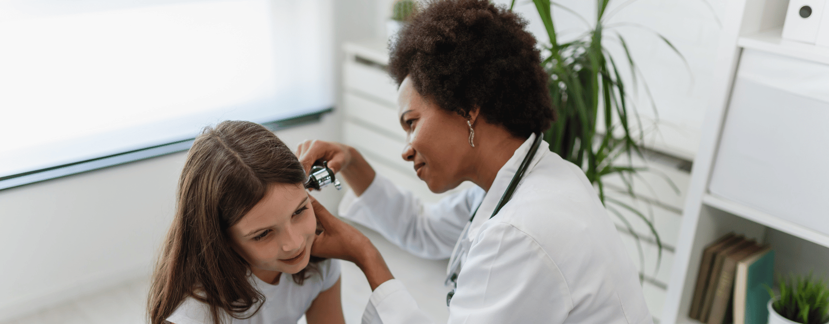 Audiologist examining a patient's ear with an otoscope during an on-site hearing evaluation